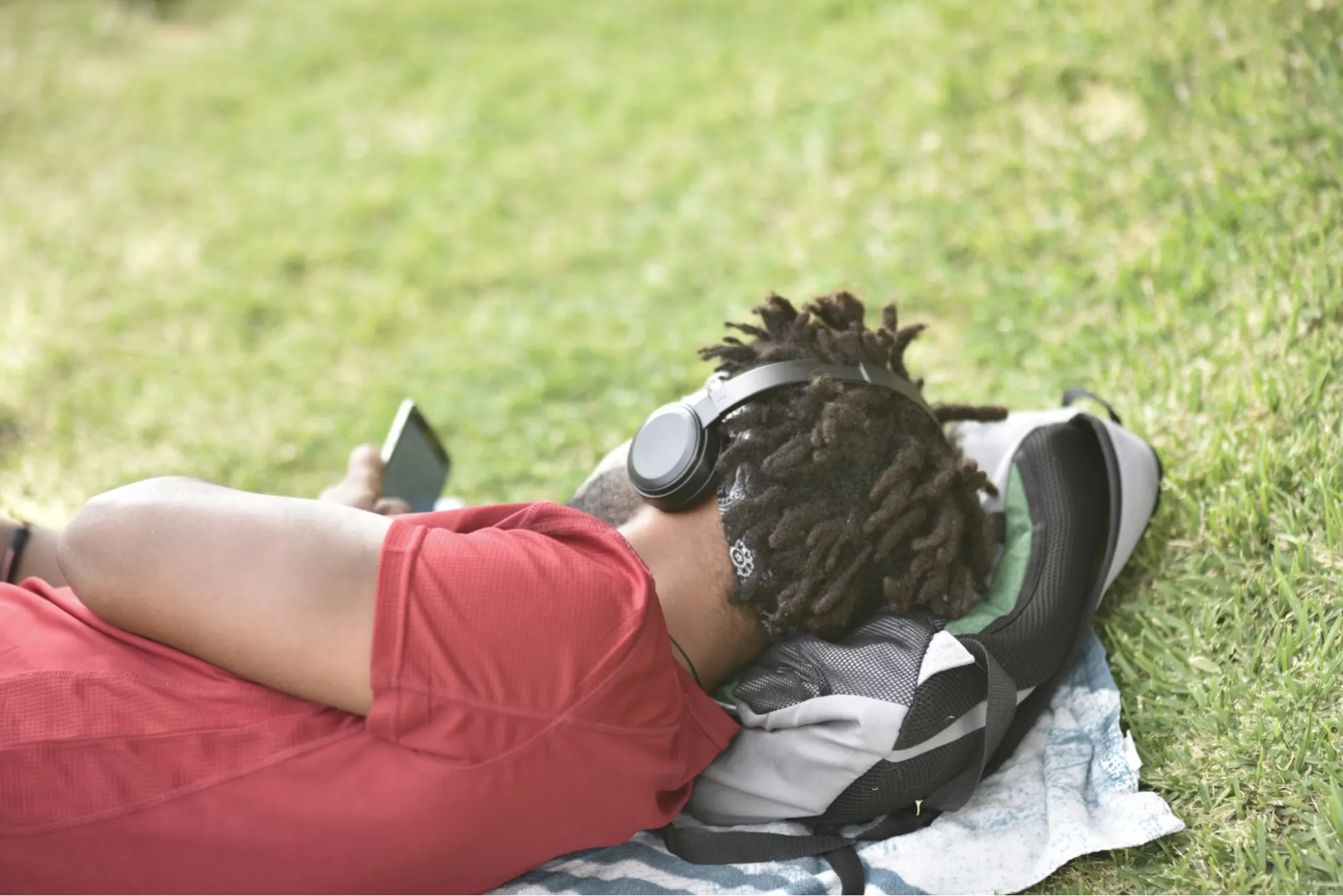 Person laying in the grass using a smartphone