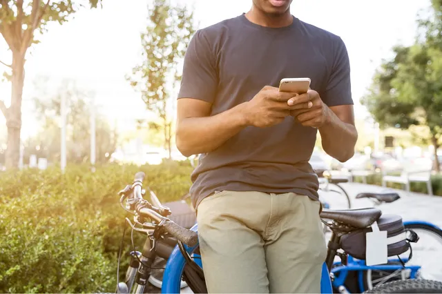 Smartphone user reviewing rich push notifications while leaning on a bike outdoors