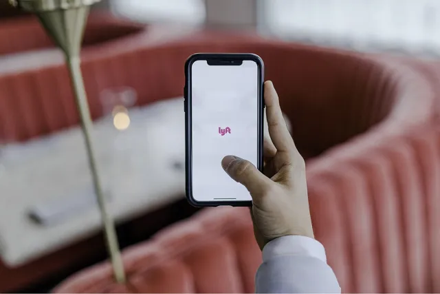 Person's hand holding smartphone opening Lyft application