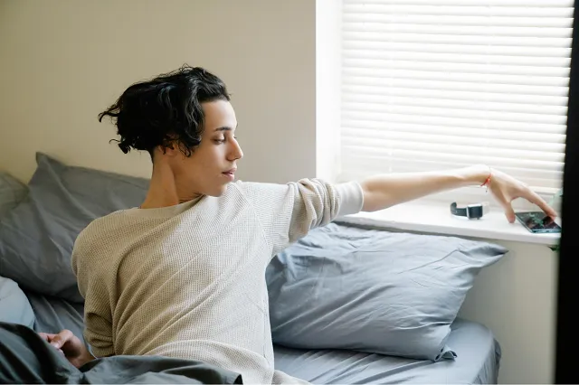 Person picking up a smartphone from a window sill after receiving a notification