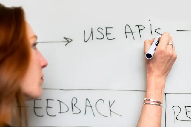 Person writing "Use APIs" on a whiteboard