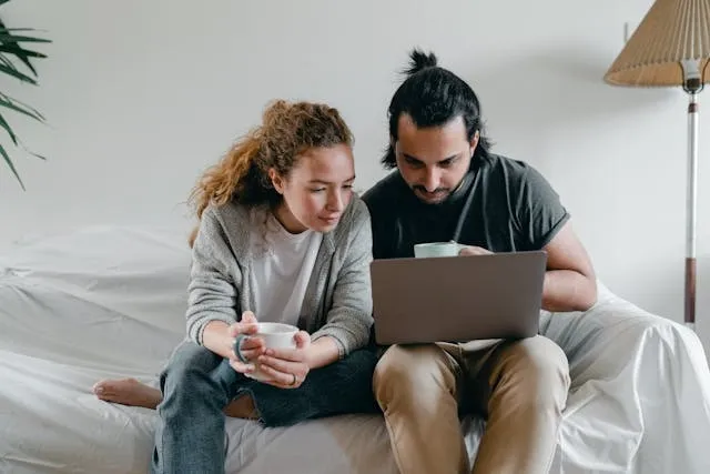 Two people browsing the web on a laptop