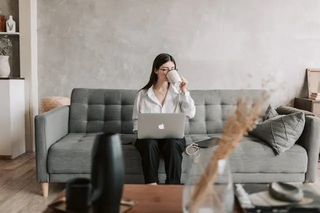 Person sitting on a couch with a laptop and tablet