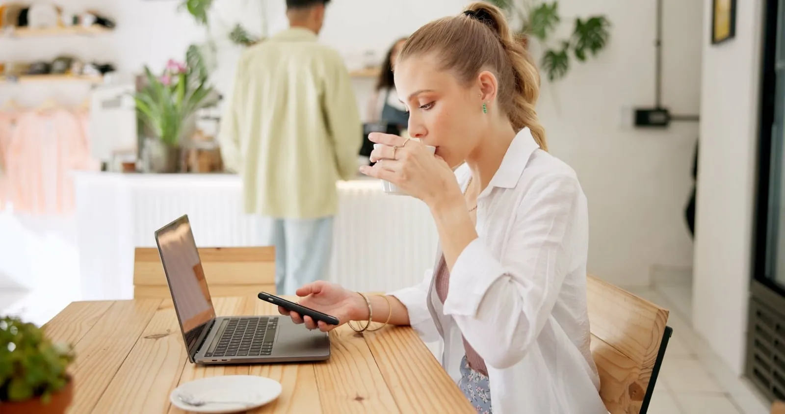 Person drinking from a coffee cup while looking at smartphone 